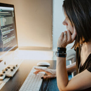 a woman seating in front of a computer monitor coding