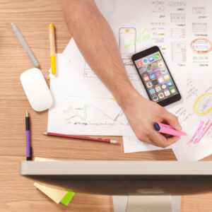 a photo of a hand holding a pink highlighter pen while scribbling on printed paper